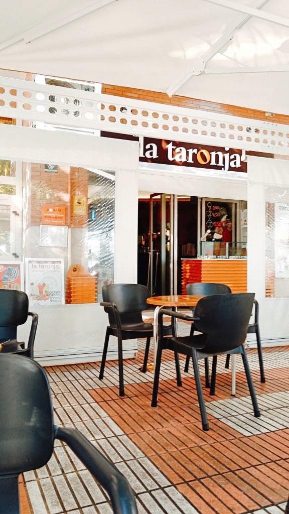 Terrace tables in daylight, under the awning and facing the La Taronja sign