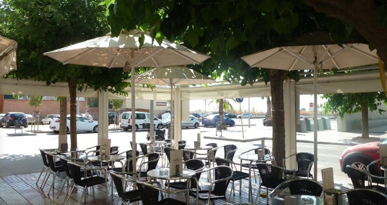 La Taronja 2's terrace with tables under white parasols and trees